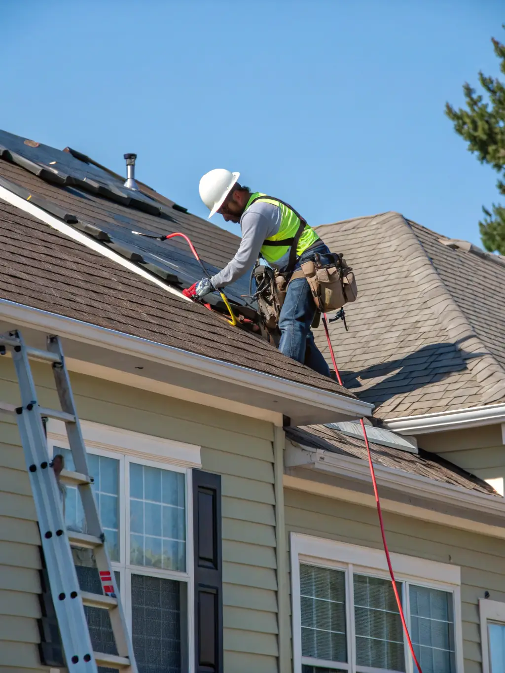 A high-angle, detailed shot of asphalt shingles being installed on a residential roof by a Ted's Roofing professional, showcasing the texture and quality of the material.